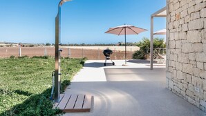 A patio area with a barbecue grill, outdoor seating, and a view of the countryside. - Villa La Siesta - Ragusa (Ragusa)