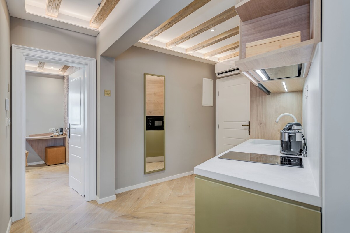 A modern kitchen with a built-in oven, a coffee machine, and a wooden ceiling.