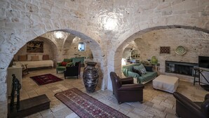 A stone-walled living room with a fireplace, sofas, and a large vase.