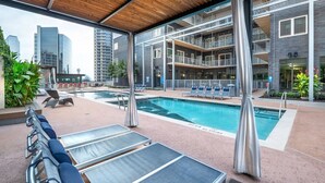A rooftop pool area with lounge chairs and a view of the city skyline.