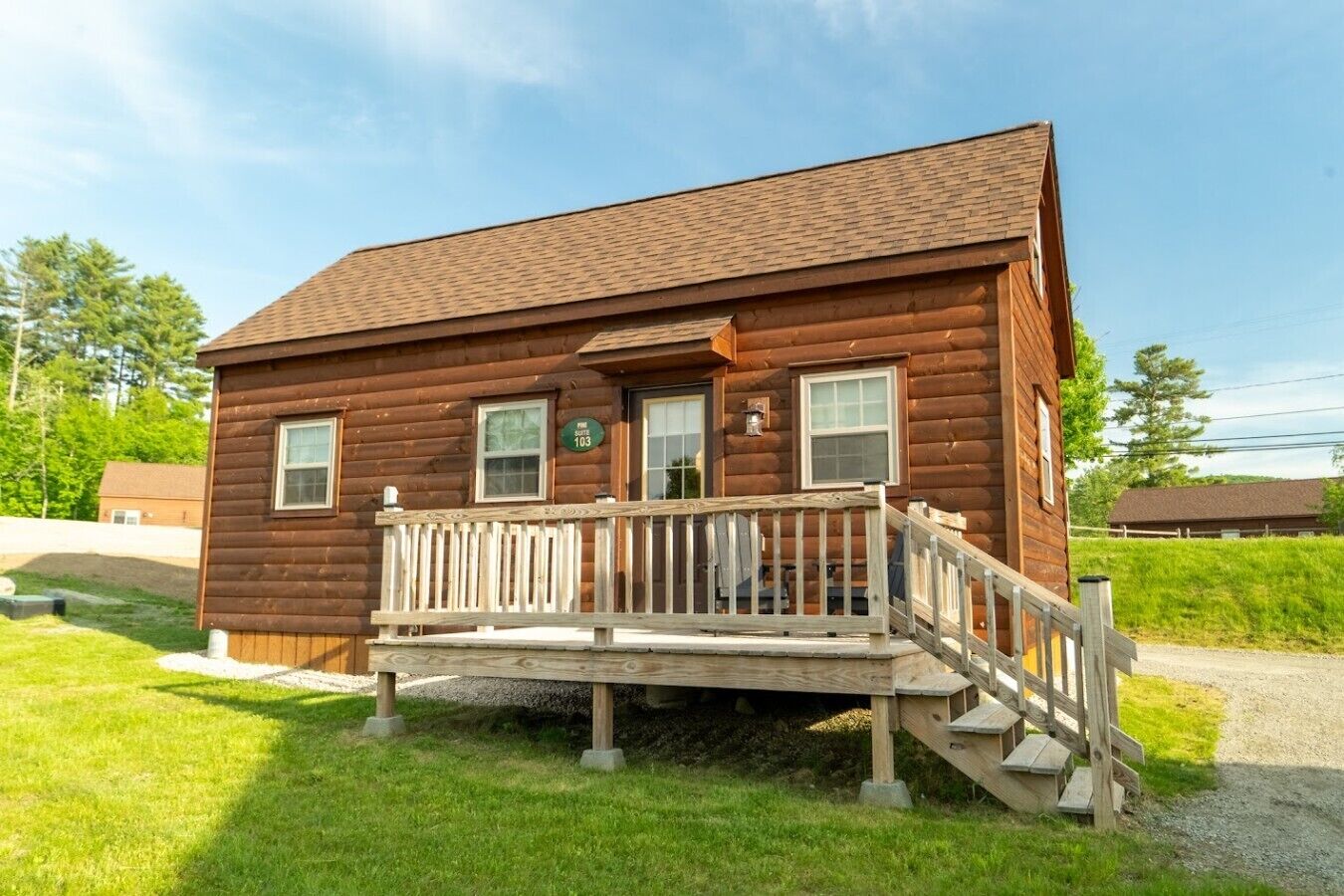 A two-story log cabin with a front porch and a small staircase leading to the entrance.