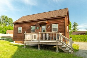 A two-story log cabin with a front porch and a small staircase leading to the entrance. - Pet Friendly Cabin with Private Fire Pit (Bethlehem)
