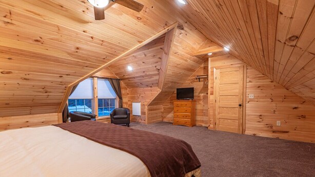 Un dormitorio con cama, una silla, cómoda y televisor.