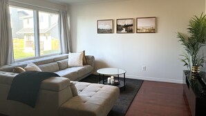 Un salon avec un canapé, une table basse ronde et un lampadaire. Trois tableaux encadrés sont accrochés au mur.
