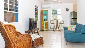 A living room with wicker furniture, a blue sofa, and a television. - Kasita di Mama (Kralendijk)
