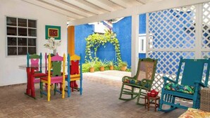 A room with a colorful play area, a bed with a floral bedspread, and a view of a garden through a lattice door. - Kasita di Mama (Kralendijk)