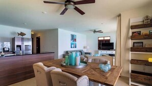 Une cuisine moderne dotée d’un îlot central, d’un coin repas avec une table et des chaises en bois, et d’un ventilateur de plafond.