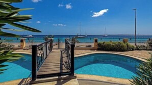 Un espace piscine doté d’une terrasse en bois et offrant une vue sur la mer.