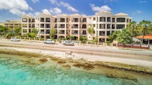 Un hôtel à plusieurs étages doté de balcons, offrant une vue sur la plage et disposant d’un parking.