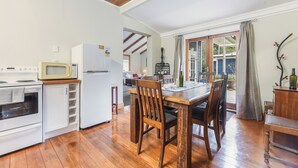 A kitchen with wooden flooring, white cabinets, a microwave, and a refrigerator. - Fantail Cottage Kaiuma Bay - Havelock Holiday Home (Havelock)