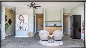 A modern living room with a ceiling fan, two sofas, a coffee table, and a large painting on the wall. - Villa Valena Apartments 3 (Kralendijk)