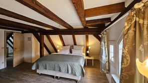 A bedroom with a bed, wooden beams, a nightstand, and a window with curtains. - Altes Pfarrhaus Hotel und Restaurant (Bad Ueberkingen)