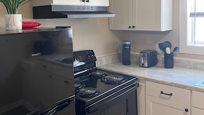Eine Küche mit weißen Schränken, einem schwarzen Herd und einem Toaster auf der Arbeitsfläche.