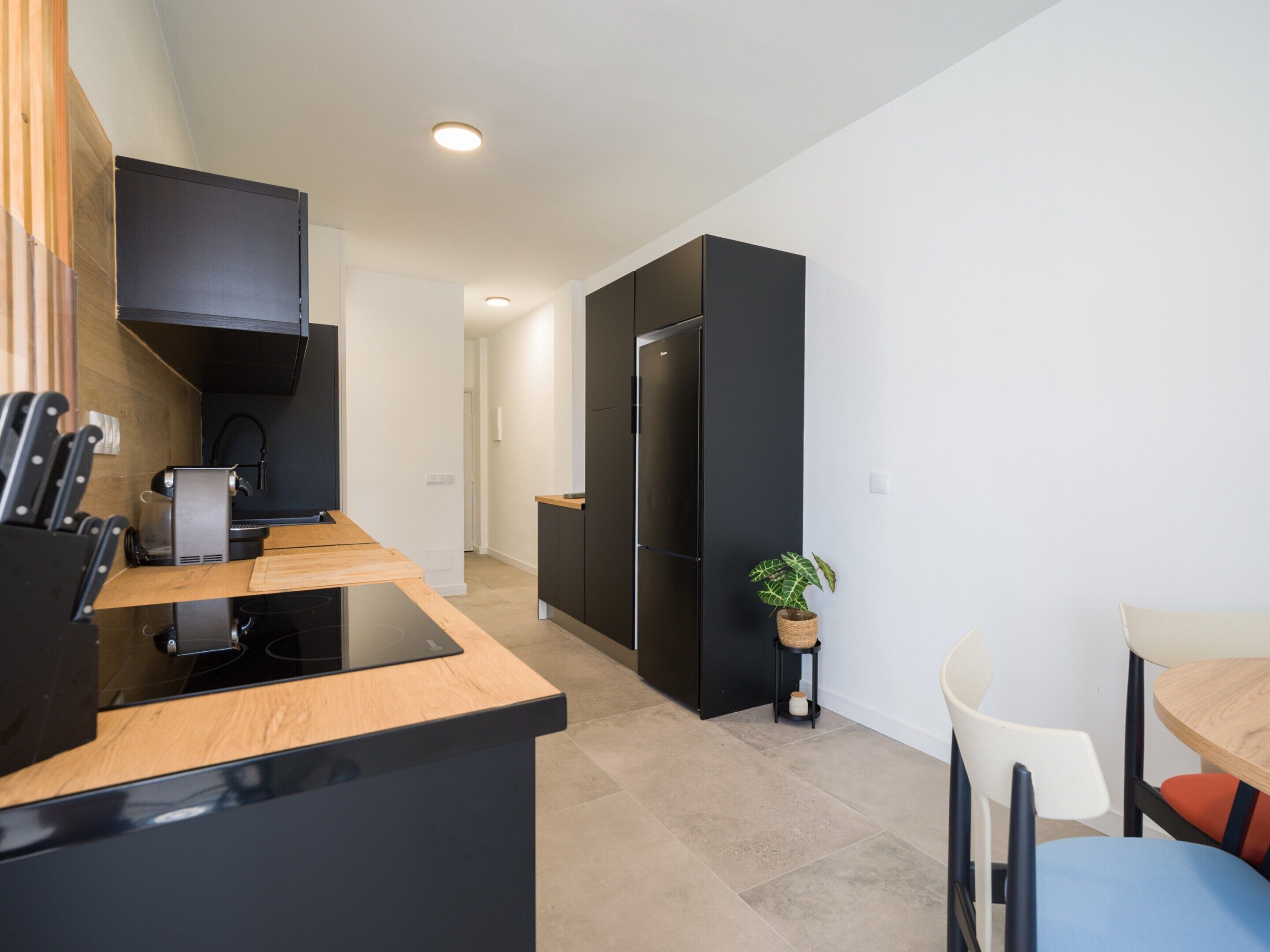A modern kitchen with a black countertop, a coffee machine, and a plant.