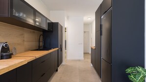 A modern kitchen with dark cabinetry, a wooden countertop, and a built-in oven. - Apartment in Gran Canaria Near Maspalomas Dunes (San Bartolomé de Tirajana)