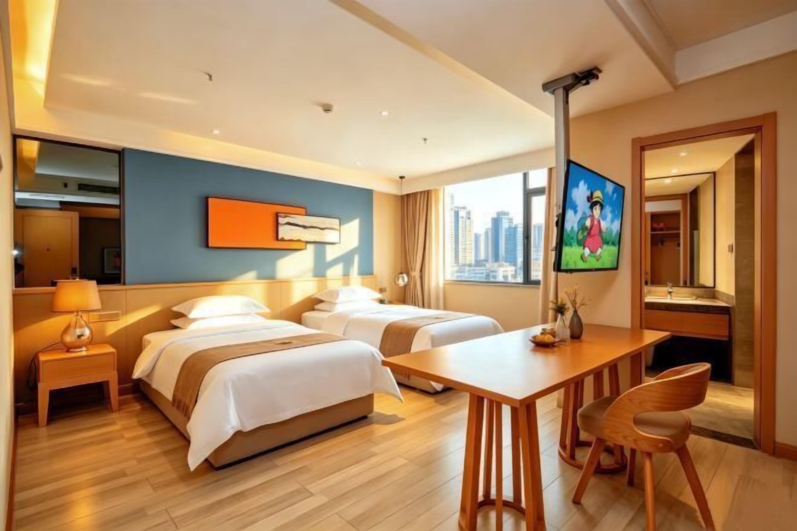 A hotel room with two beds, a desk, a chair, a TV, and a city view.