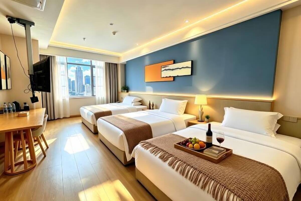 A hotel room with two beds, a desk, a TV, and a city view.