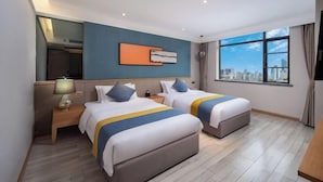 A hotel room with two beds, a large window with a city view, a modern art piece on the wall, and a nightstand with a lamp. - Qifan Hotel (Kunming Railway Station Huannan South Road Metro Station Branch) (Kunming)