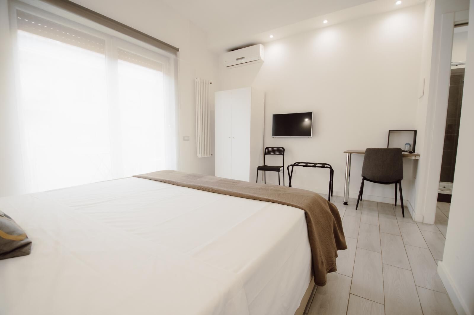 Ein Hotelzimmer mit einem großen Bett, einem Schreibtisch mit Stuhl, einem Fernseher und einer Heizung.