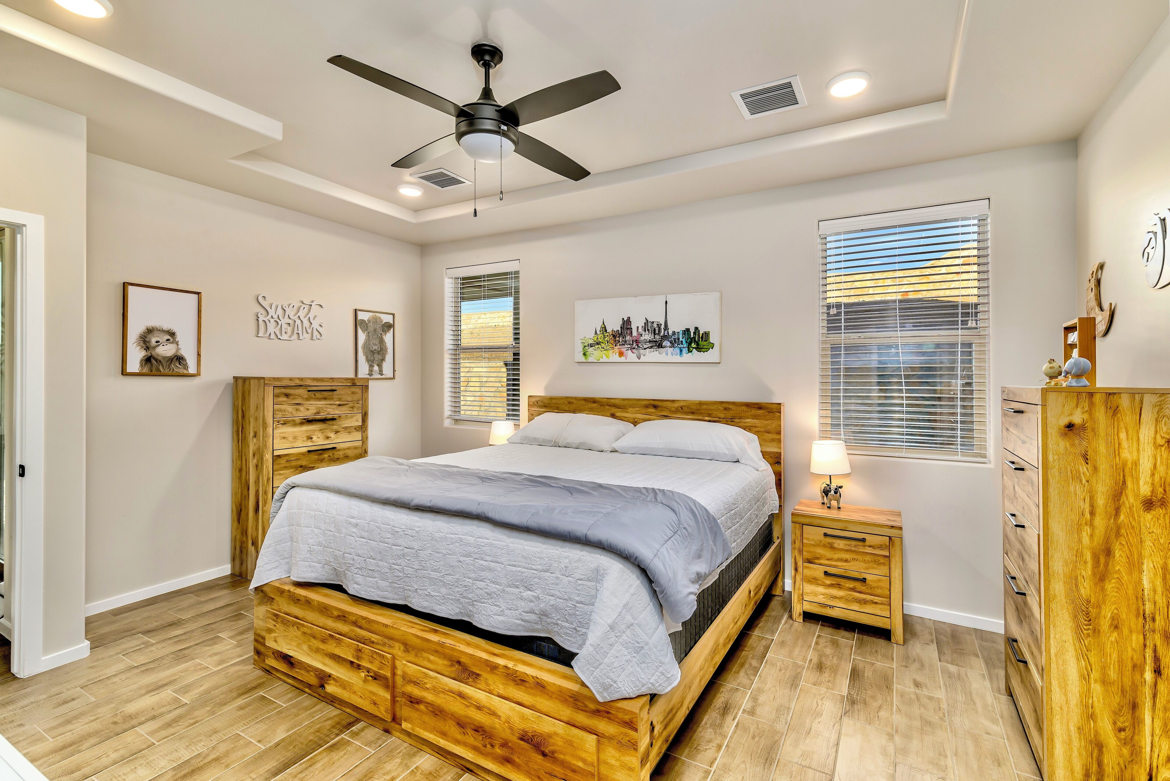 A bedroom with a wooden bed, a ceiling fan, and a nightstand with a lamp.
