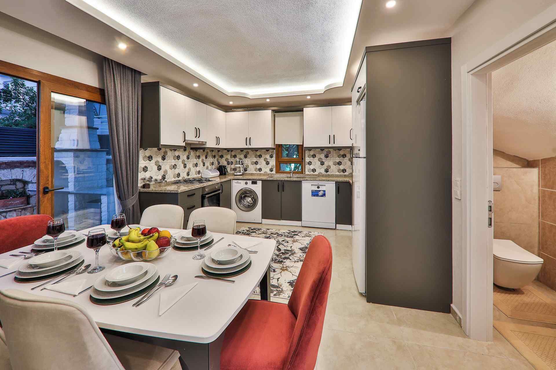 A modern kitchen with white cabinets, a built-in oven, and a washing machine.