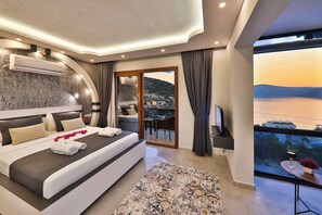 Una camera da letto moderna con un letto grande, vista sul mare e un balcone con tavolo e sedia.