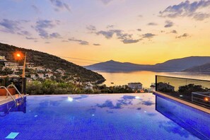 A swimming pool with a view of a coastal town at sunset. - Villa Rainbow (Kas)