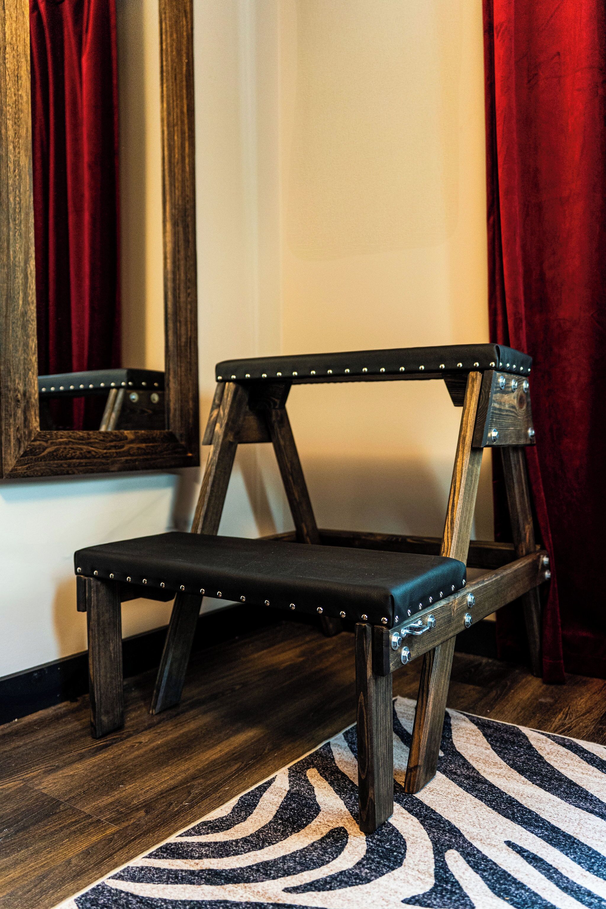 A chair with a wooden frame and metal studs, positioned on a patterned rug.