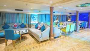 A spacious lobby with a herringbone floor, a central seating area with sofas and chairs, and a large stained glass window above.