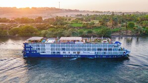 A river cruise ship with multiple decks, outdoor seating areas, and a swimming pool.