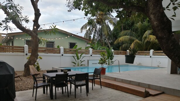 Ein Garten mit Pool, Holzterrasse und Gartenmöbeln.