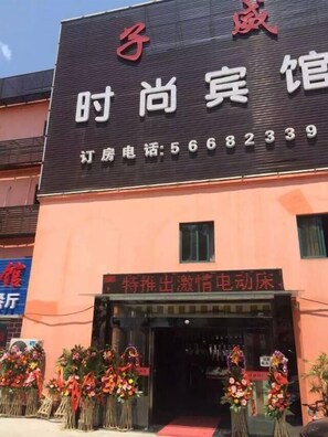 A hotel with a black facade and red signage. There are flower arrangements outside the entrance. - Ziwei Shishang Hotel (Shanghai)