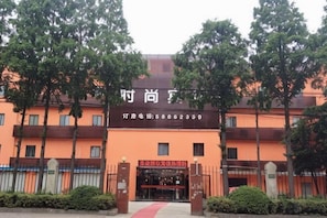 A building with a sign that reads 'Hotel Name' and a contact number. There are trees in front of the building.