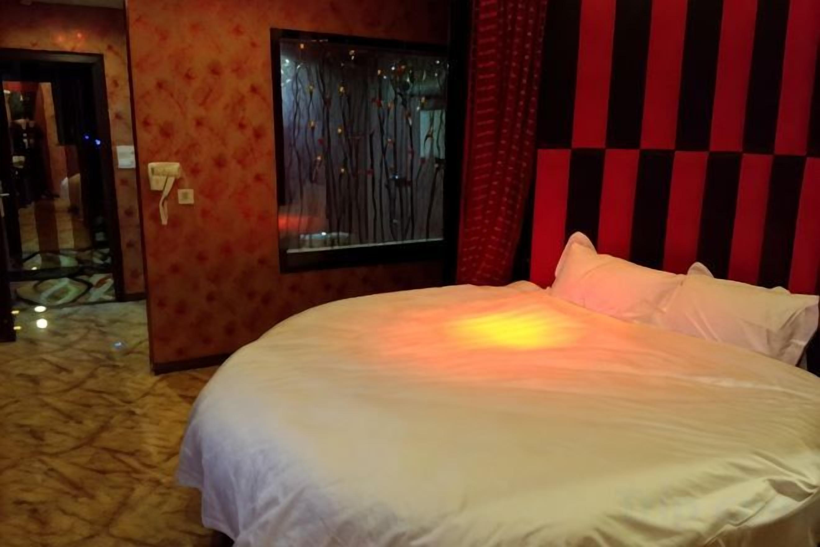 A hotel room with a large bed, a window with curtains, and a patterned wall.
