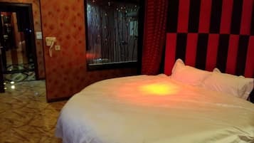 A hotel room with a large bed, a window with curtains, and a patterned wall.