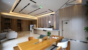 A modern hotel lobby with a wooden reception desk, seating area, and a large window. - Rest Comfort Hotel (Wenzhou Oubei Shuangta Road) (Yongjia)