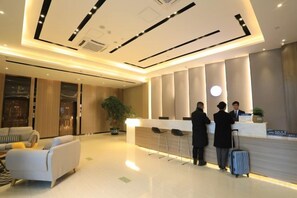 A modern hotel lobby with a reception desk, seating area, and a large potted plant. - Rest Comfort Hotel (Wenzhou Oubei Shuangta Road) (Yongjia)