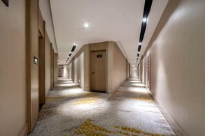 A hotel corridor with a patterned floor, wooden doors, and recessed lighting. - Rest Comfort Hotel (Wenzhou Oubei Shuangta Road) (Yongjia)
