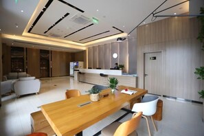 A modern hotel lobby with a reception desk, seating area, and a large wooden table. - Rest Comfort Hotel (Wenzhou Oubei Shuangta Road) (Yongjia)
