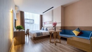 A modern hotel room with a bed, a sofa, a desk, and a small table. - Rest Comfort Hotel (Wenzhou Oubei Shuangta Road) (Yongjia)
