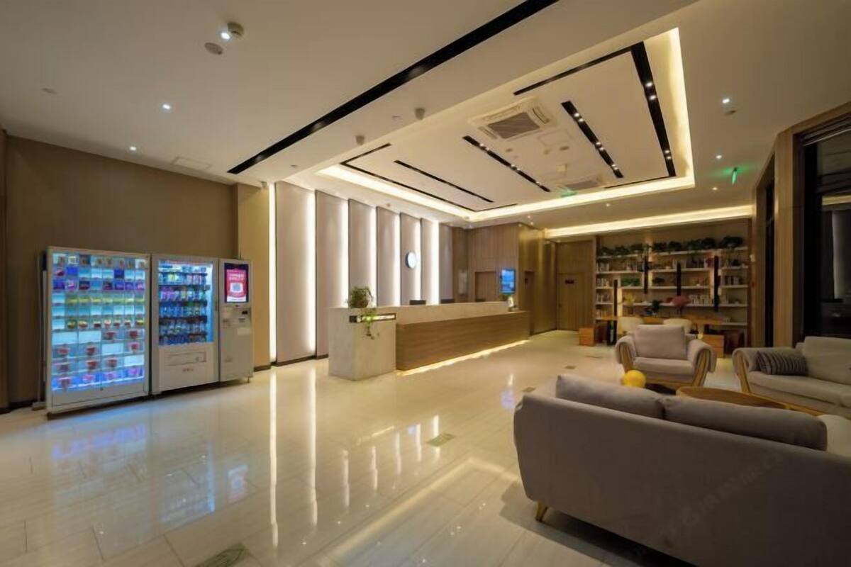 A hotel lobby with a reception desk, seating area, vending machines, and a bookshelf.