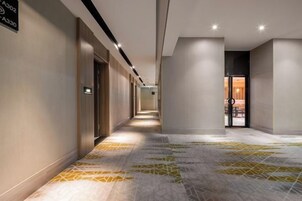 Pasillo de hotel con piso estampado, puertas y un letrero que indica los tipos de habitaciones.