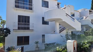 A multi-story building with balconies, a staircase, and a garden area.