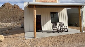 Un bureau de poste américain situé à Terlingua, au Texas, avec une façade en bois, un porche en béton et une chaîne de montagnes en arrière-plan.