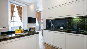 A modern kitchen with white cabinetry, a granite countertop, and a built-in stove. - Alta Luxury Apartments - Spagna Apartment (Rome)