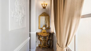 A hallway with a gold-framed mirror, a wall-mounted clock, and a light fixture. - Alta Luxury Apartments - Spagna Apartment (Rome)