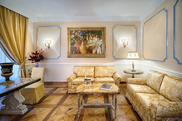 A room with a sofa, a coffee table, a lamp, and a painting on the wall. - Alta Luxury Apartments - Frezza Apartment (Rome)