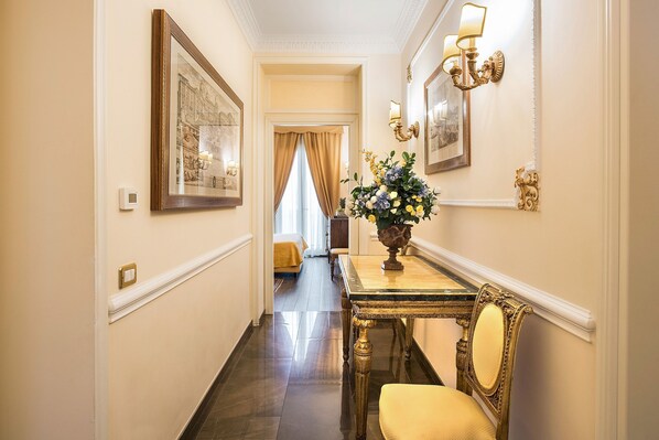 A hallway with a dining table, chairs, and a vase of flowers.