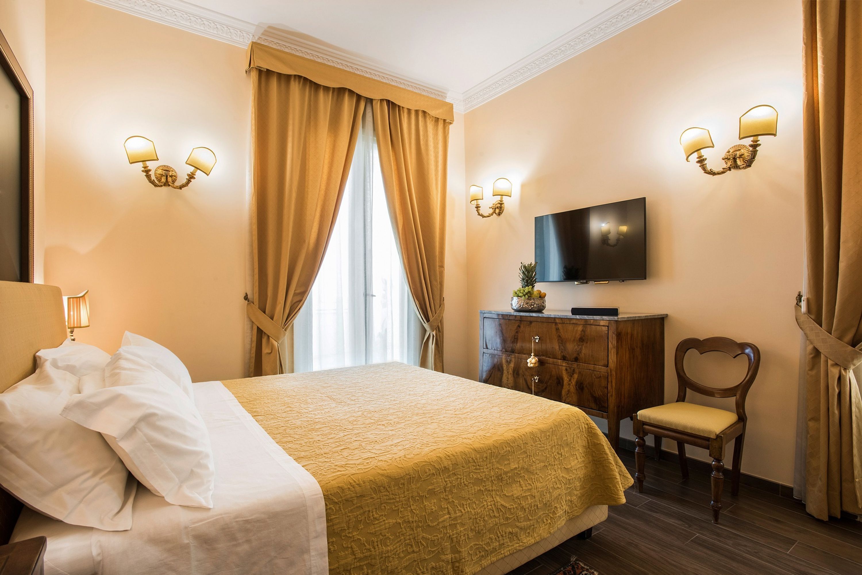 Habitación de hotel con una cama grande, un aparador de madera, un televisor y una silla.