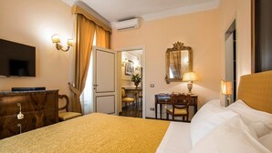 A hotel room with a large bed, a desk with a lamp, a television, and a wardrobe. - Alta Luxury Apartments - Oca Apartment (Rome)
